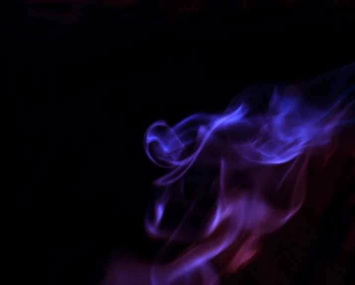 purple flames on a black background with other colored smoke