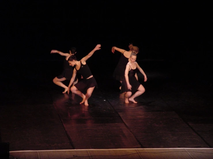 dancers perform on stage with dark lighting