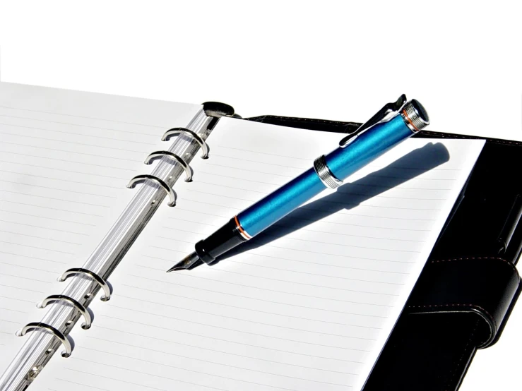 a notebook with a pen attached is on the desk