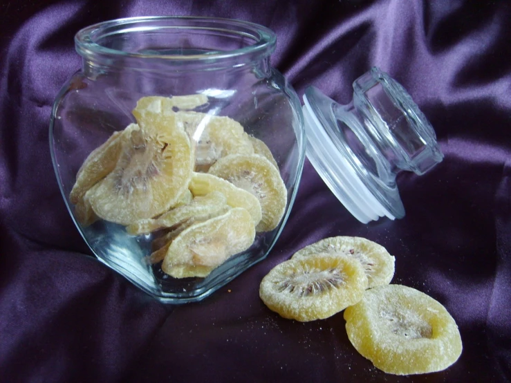 peeled bananas in a glass jar next to a bowl with a lid
