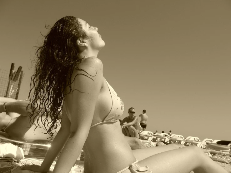 a woman sitting on a beach in a bikini