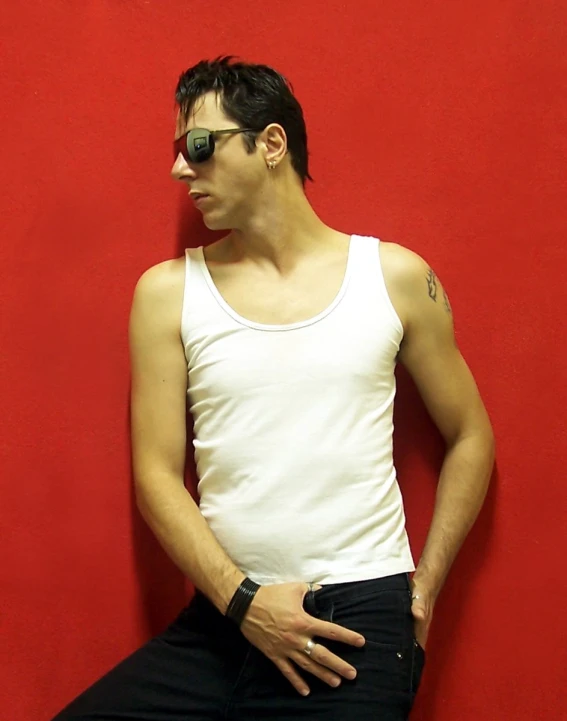 young man with black eye glasses sitting against a red wall