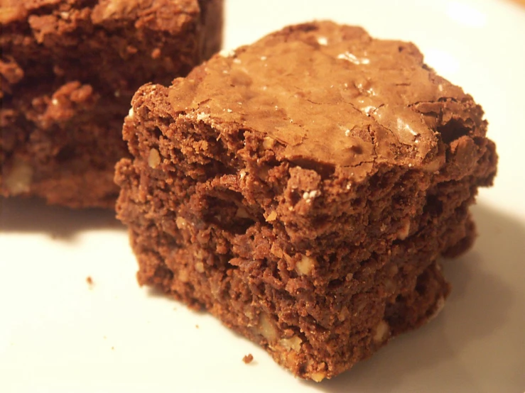 two brownies with frosting sitting on a white plate