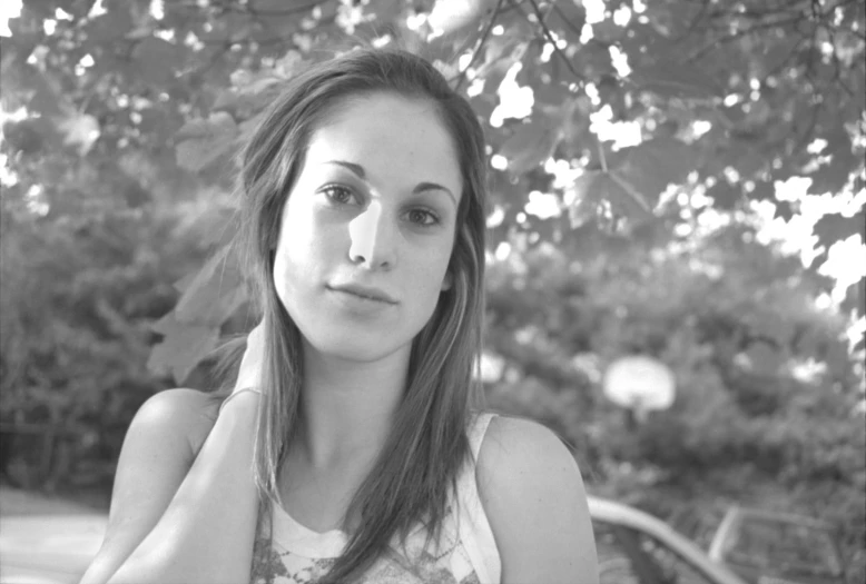 a girl sitting on top of a bench under a tree