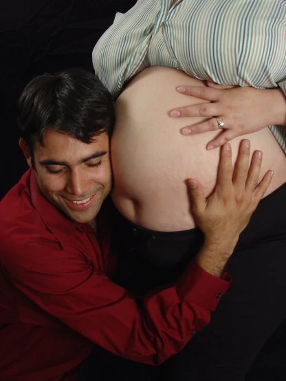 an adult smiling and hugging a pregnant man