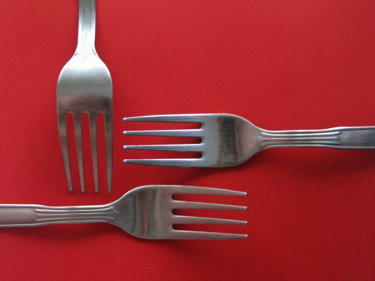 a fork and a knife are placed on a red surface