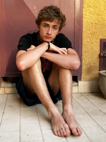 a young man sitting on the ground by his door