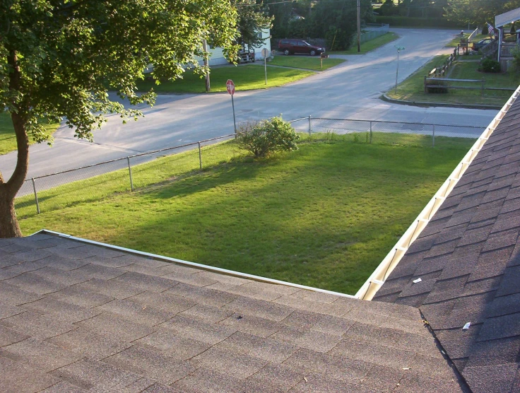 a view from an above of a grassy area, with a tree and a house in the background