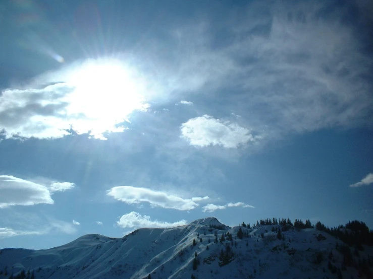 the sun is shining brightly above a snow capped mountain