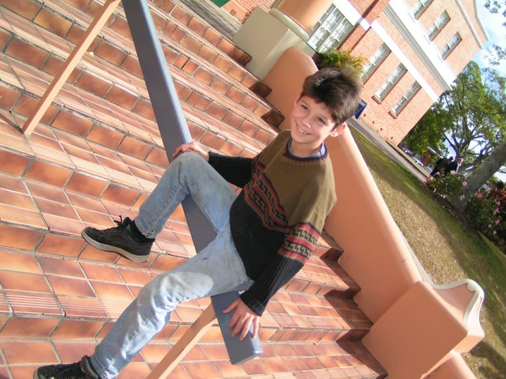 a boy is leaning against the side of a building