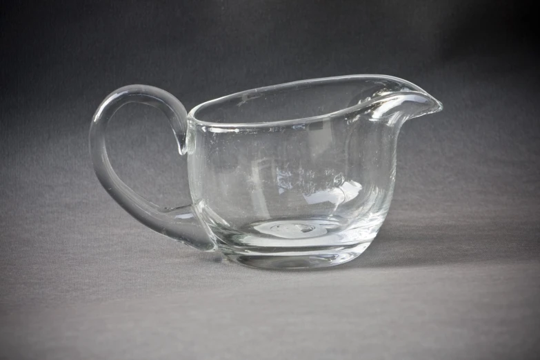 a glass pitcher sitting on a gray background