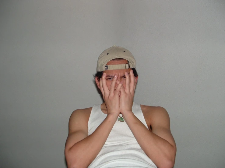 a young man covers his eyes with his hands