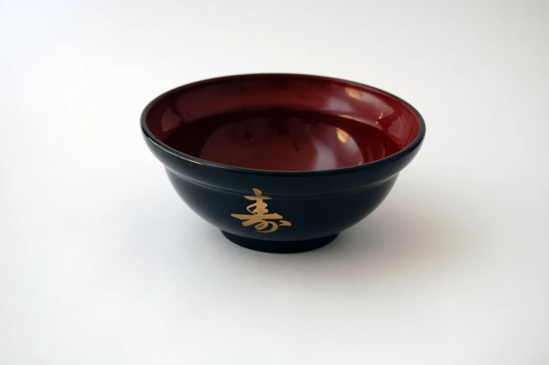 a black bowl with gold chinese writing on it