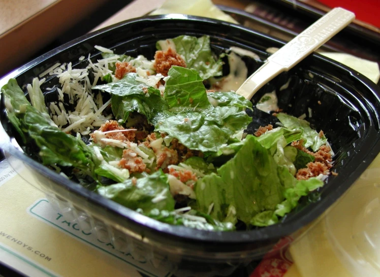 a salad in a container and spoon sitting on a table