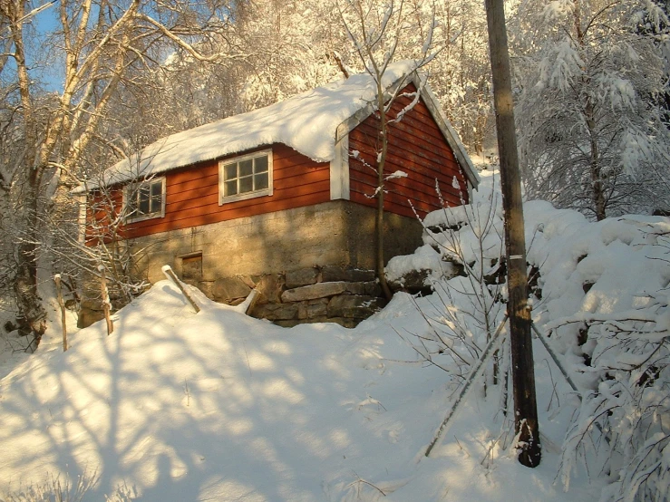 a red cabin surrounded by a thick layer of snow