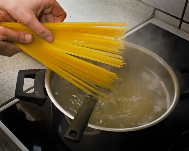 a person with long spaghetti noodles on top of a stove