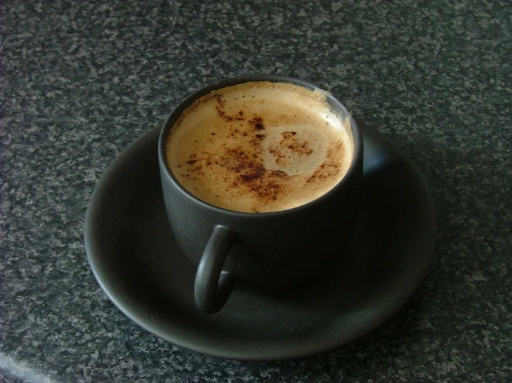 a cappuccino sits on top of a dark plate