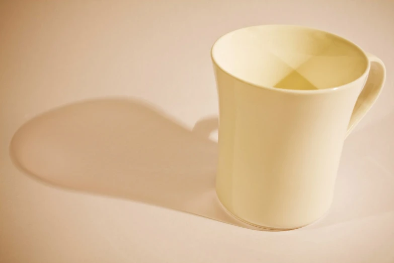 a yellow cup with a shadow on the ground