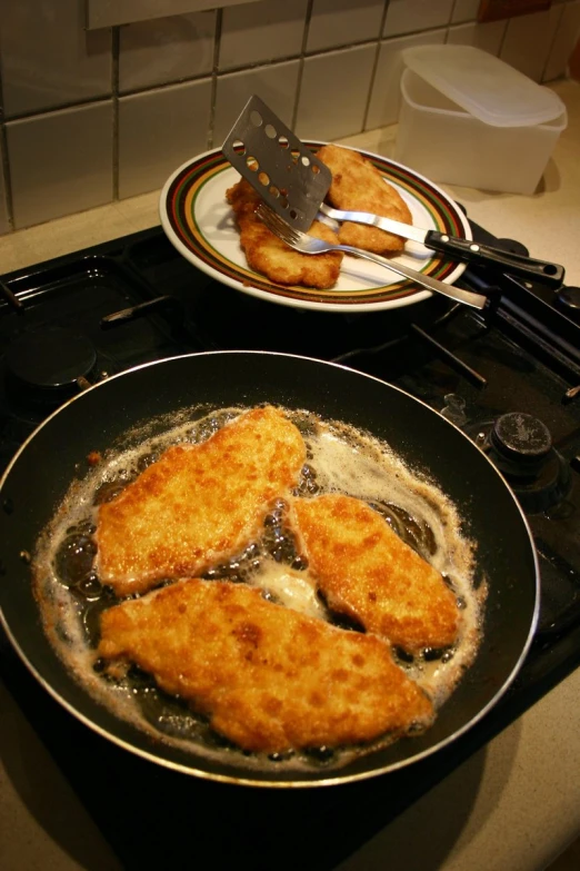 two pans filled with fish fillets sitting on top of a stove