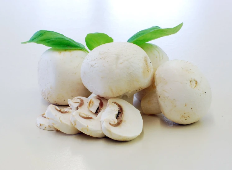 sliced mushrooms with leafy stems on a white surface