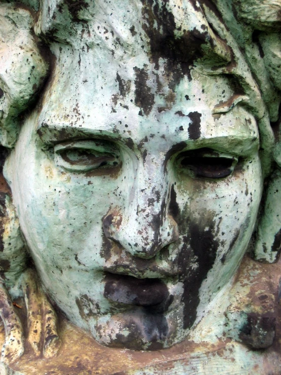 closeup of face and eyes on statue with paint splatches on its skin