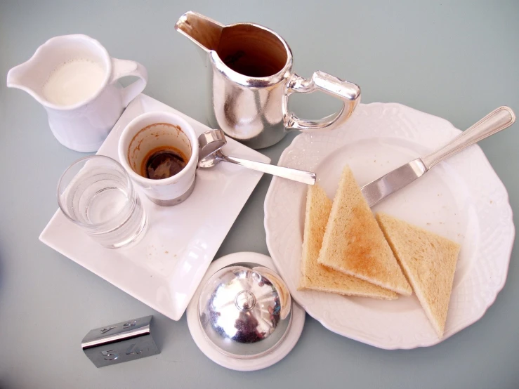 coffee cups, silver spoons, white plate, and bread and croissants