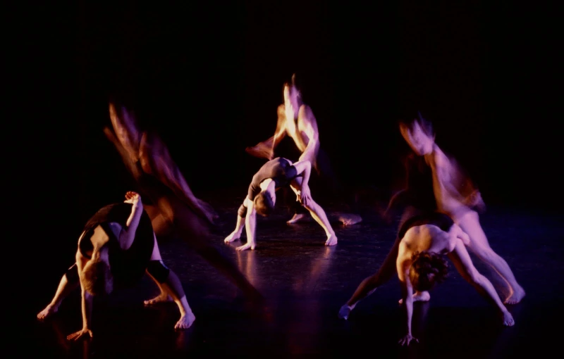 multiple people stretching out on a dark stage