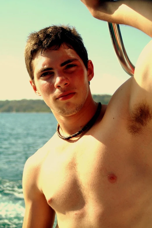 a young man that is shirtless standing next to the water