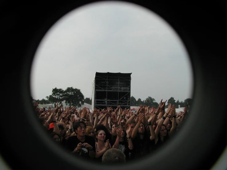 people in front of an outdoor stage from inside a telescope lens