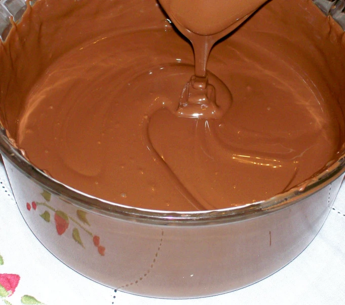 a spoon with chocolate sauce is in a large pot