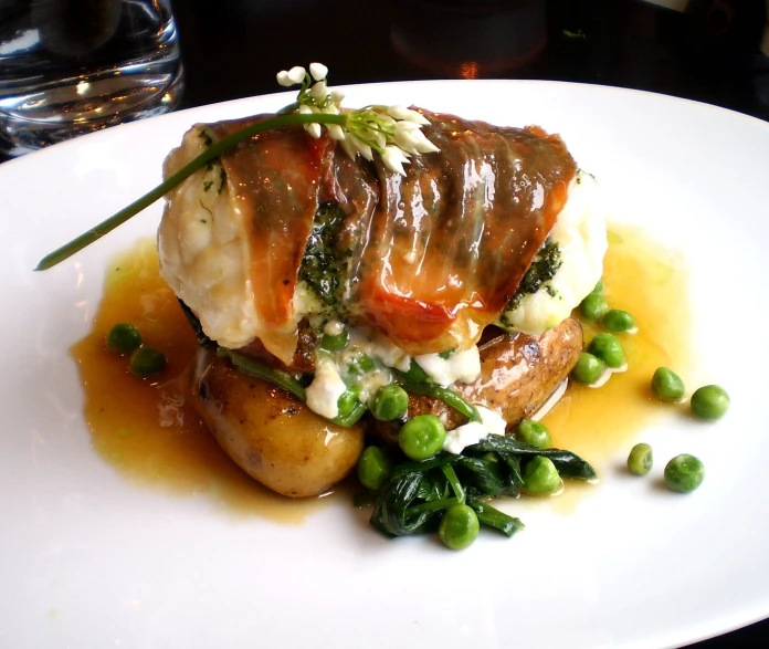 a plate topped with food covered in sauce and green peas