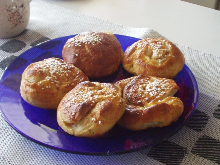 four cinnamon rolls are on a purple plate