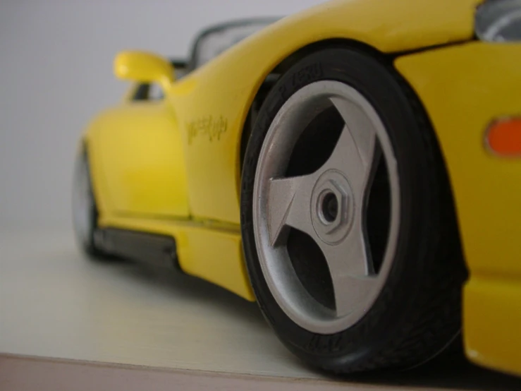 a toy car with a yellow rim and black tire