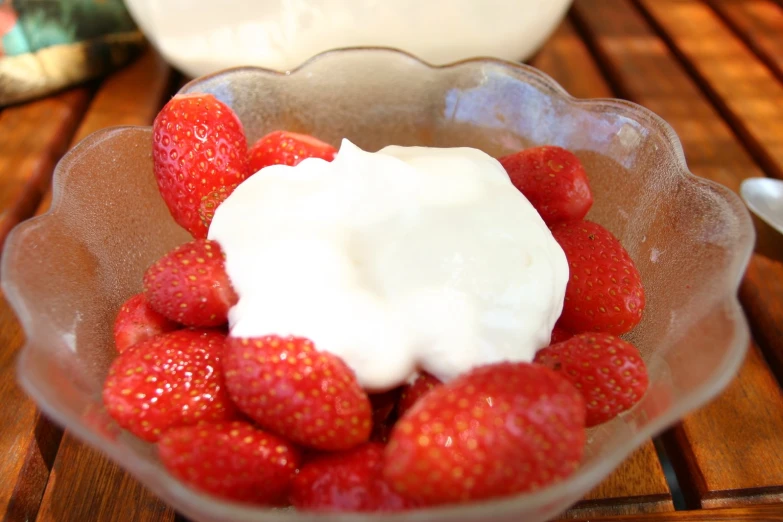 a bowl full of strawberries with some whipped cream