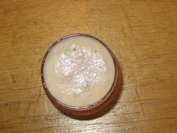 a small glass of beer sits on a table