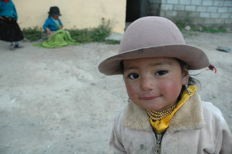 little girl with large hat in an impoverished village