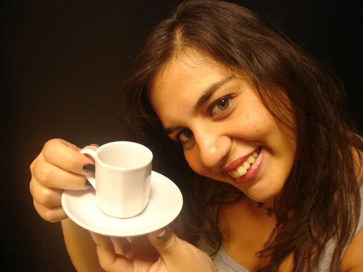a young woman holding a coffee cup and saucer