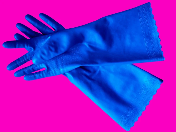 a pair of blue gloves is sitting on top of the pink background