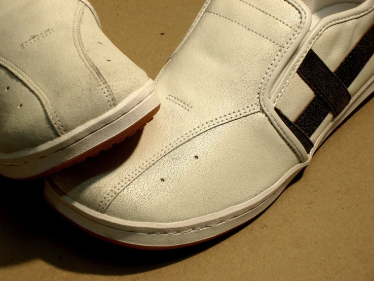 a white tennis shoe with a black cross painted on the bottom