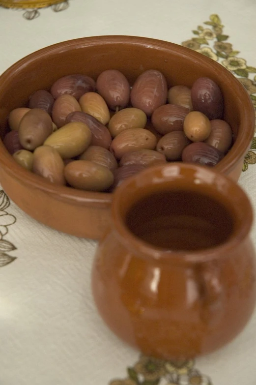 a small vase filled with nuts sitting next to a ceramic pot