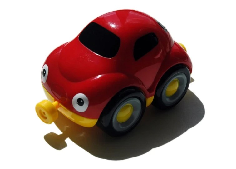 a little red toy car with eyes and a yellow handle