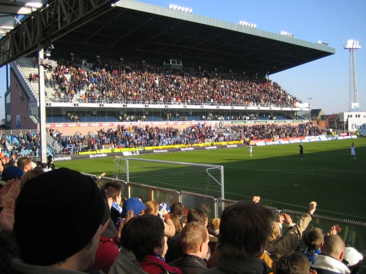 a large crowd of people standing in front of an outdoor soccer field