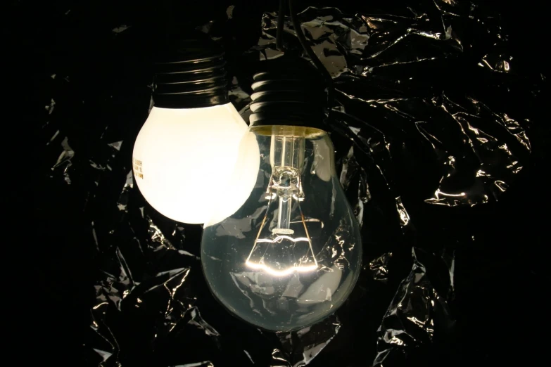 two light bulbs in the dark against crumpled metal