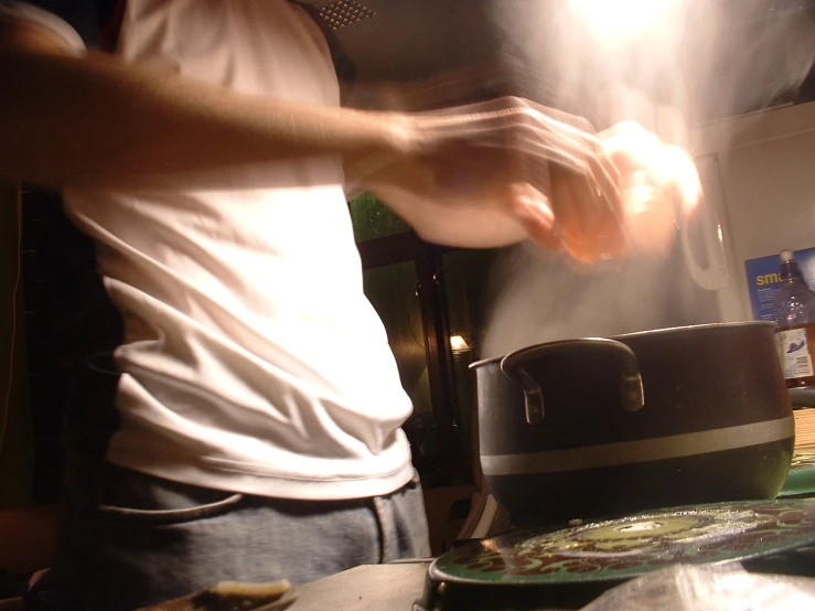 a person making food in the kitchen with steam coming out of the pots