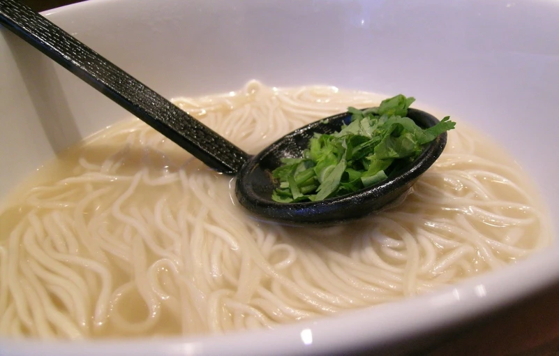 a close - up of a bowl with noodles and garnishes in it