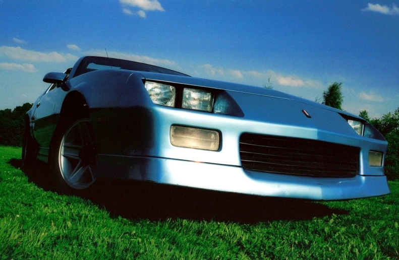 a shiny silver sports car parked in the grass