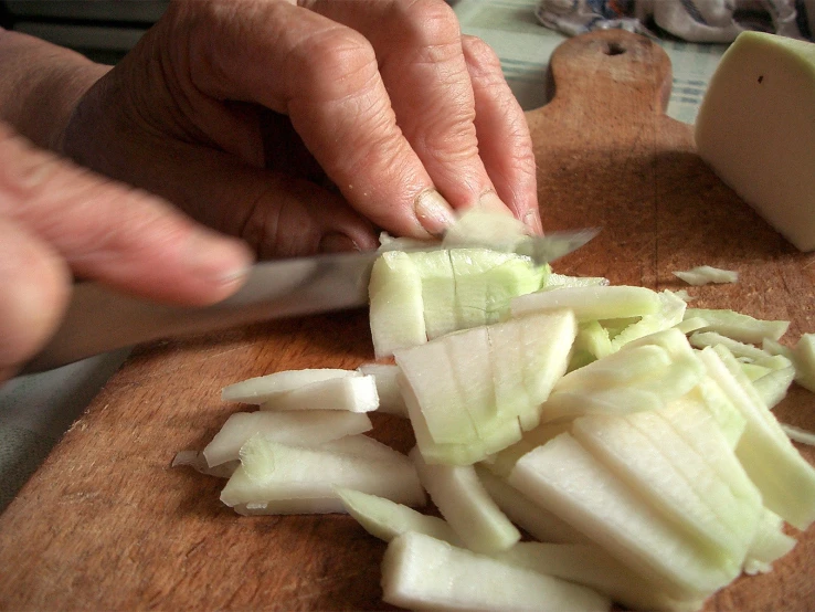 hands are  onions in to slices on a  board