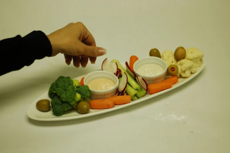 there is a white plate with vegetables and dips