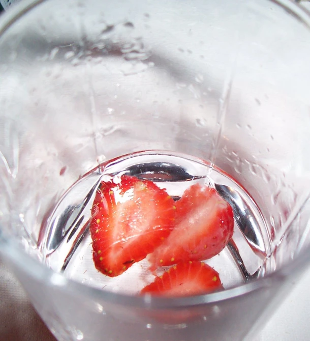 two strawberries being half frozen in a glass