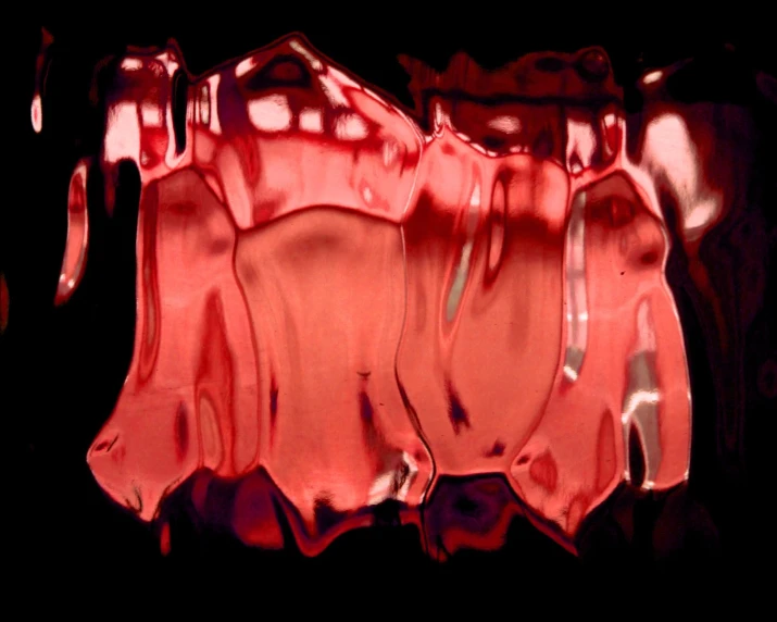 a red glass object with dark background